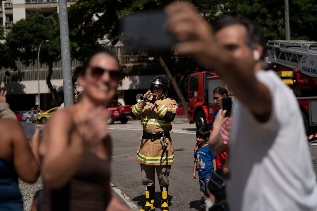 <b>Un concierto muy especial.</b> Residentes de Río de Janeiro, Brasil, se deleitan con la presentación que les hiciera el bombero y músico Elielson Silva. El artista tocó para las personas en cuarentena desde la escalera del camión de emergencia y luego bajó a la calle. 4 de abril.