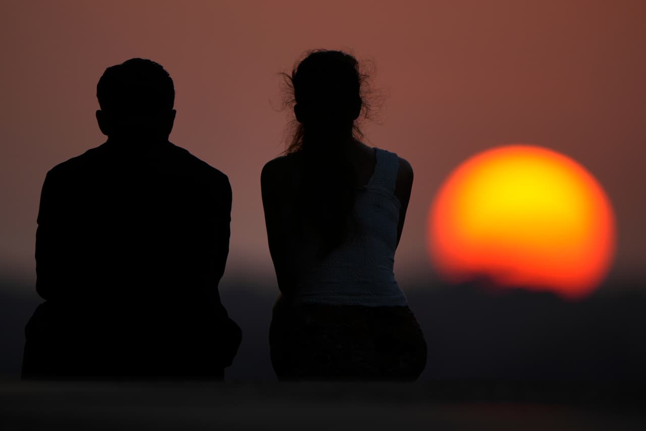 Personas observan la puesta de sol al final de un caluroso día de verano, el domingo 26 de julio de 2026, en Kansas City, Misuri.
