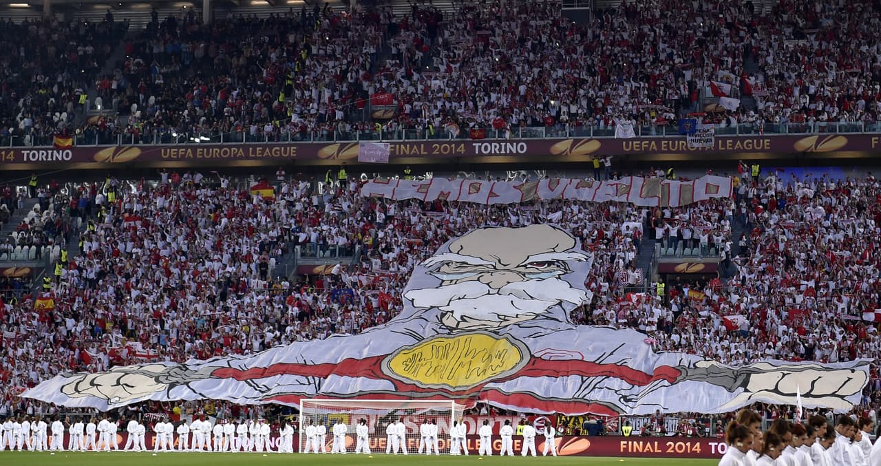 En el escudo del Sevilla FC están los tres santos patronos de la ciudad: San Isidoro, San Fernando y San Leandro. El que aparece en este megatrapo que los sevillistas usaron en la final de la Europa League 2014 en Turín es San Isidoro.