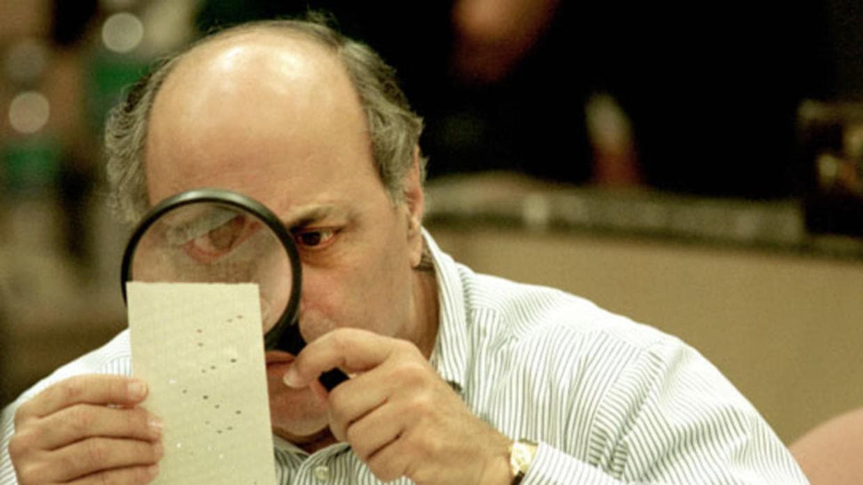 El juez Robert Rosenberg, miembro de la junta de distrito electoral del condado de Broward, examina una papeleta en el recuento de las elecciones presidenciales de 2000.