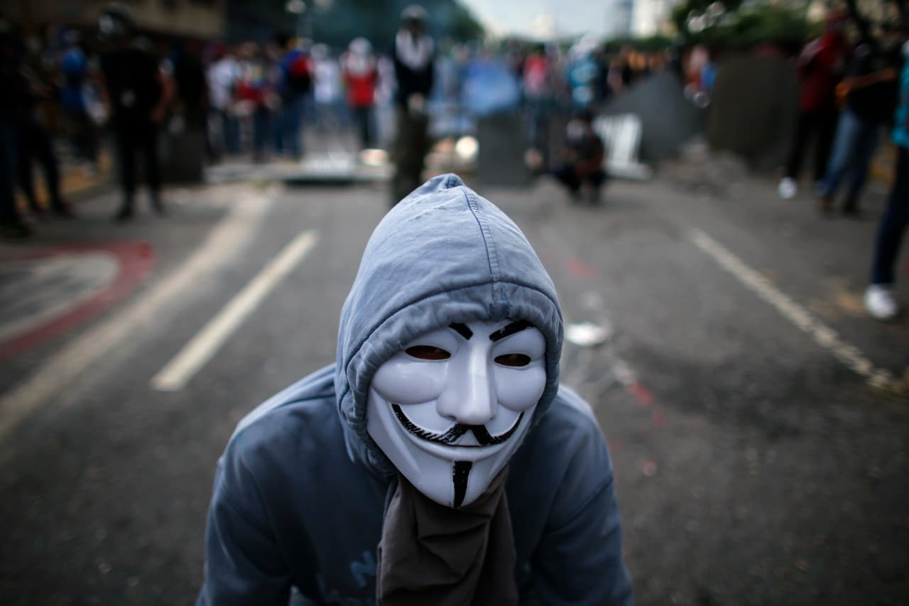 A masked opponent of President Nicolas Maduro stands at a barricade set up by protesters as security forces block protesters from reaching the national ombudsman office in Caracas, Venezuela, Wednesday, April 26, 2017. Hundreds of thousands of Venezuelans have flooded the streets over the last month to demand an end to Maduro's presidency. (AP Photo/Ariana Cubillos)