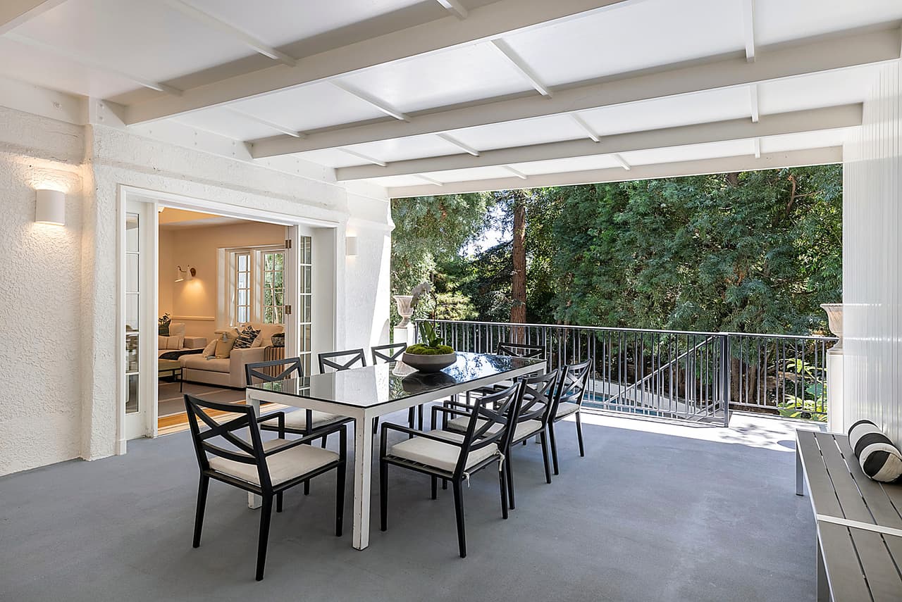 Hay un comedor en la terraza con vista al jardín.