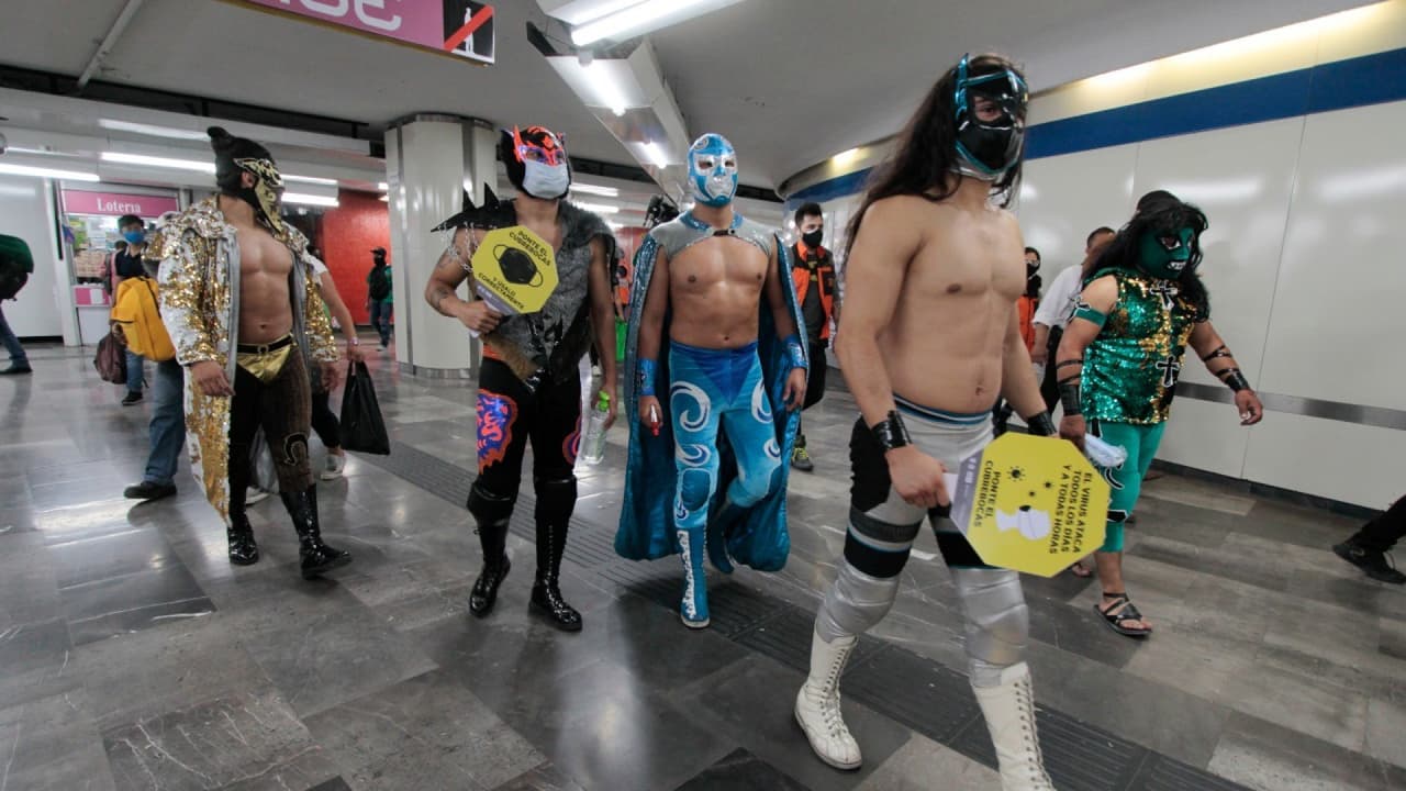 Luchadores reparten cubrebocas en el metro de México