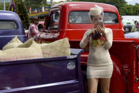 Una mujer toma fotos durante un desfile de coches clásicos en el marco del Festival de las Flores de Medellín, en Colombia.
