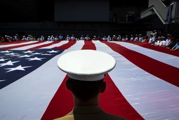 Miembros de las fuerzas armadas despliegan una bandera estadounidense durante una ofrenda floral en la ceremonia del Memorial Day, en Nueva York.