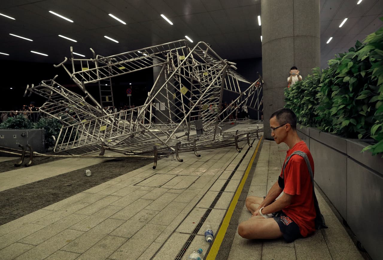 Al finalizar los enfrentamientos entre la policía y los manifestantes, este hombre se sentó en actitud meditativa. Al fondo se ven las barreras que fueron movidas por los que participaron en la protesta contra la pretendida ley de extradición de Hong Kong.