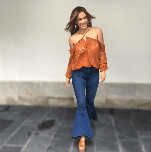 Consigue un estilo 'hippie' usando pantalones con botones al frente, zapatos de plataforma y blusa con hombros al descubierto.