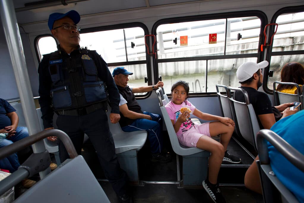 Una niña se sienta cerca de un agente de la policía en la parte trasera de un camión del transporte público, en la Ciudad de México.