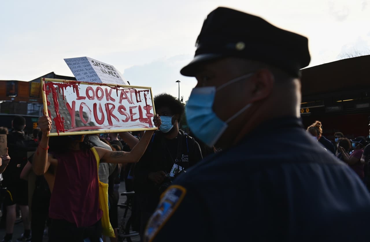 "Mírate a tí mismo": una chica con un espejo apunta a un policía de origen afroamericano.