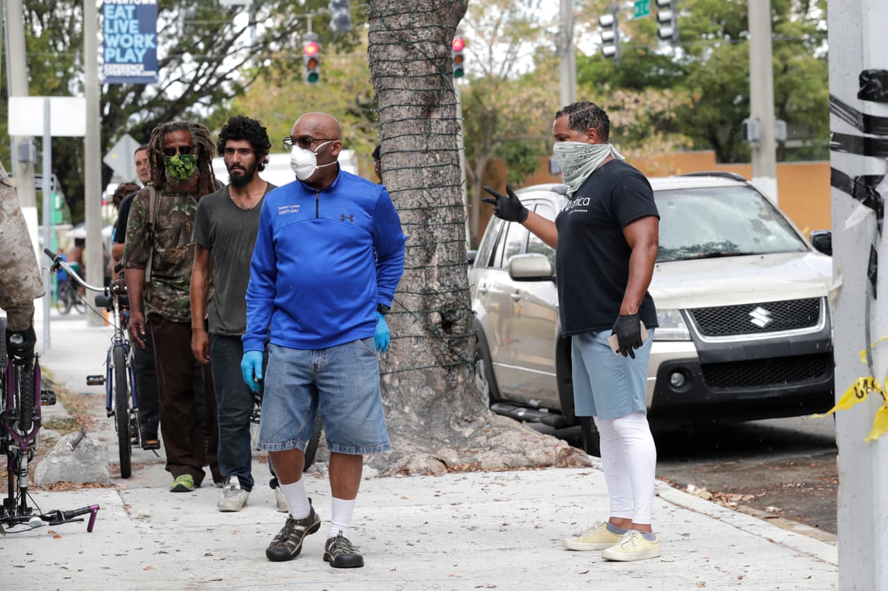 En esta imagen, Derek Fleming, socio del chef Marcus Samuelsson, controla la fila de personas que esperan fuera de su restaurante Red Rooster en Miami, en donde recibirán una comida gratis. Samuelsson forma parte de la World Central Kitchen del chef Jose Andres, que distribuye comidas gratis a los más necesitados.