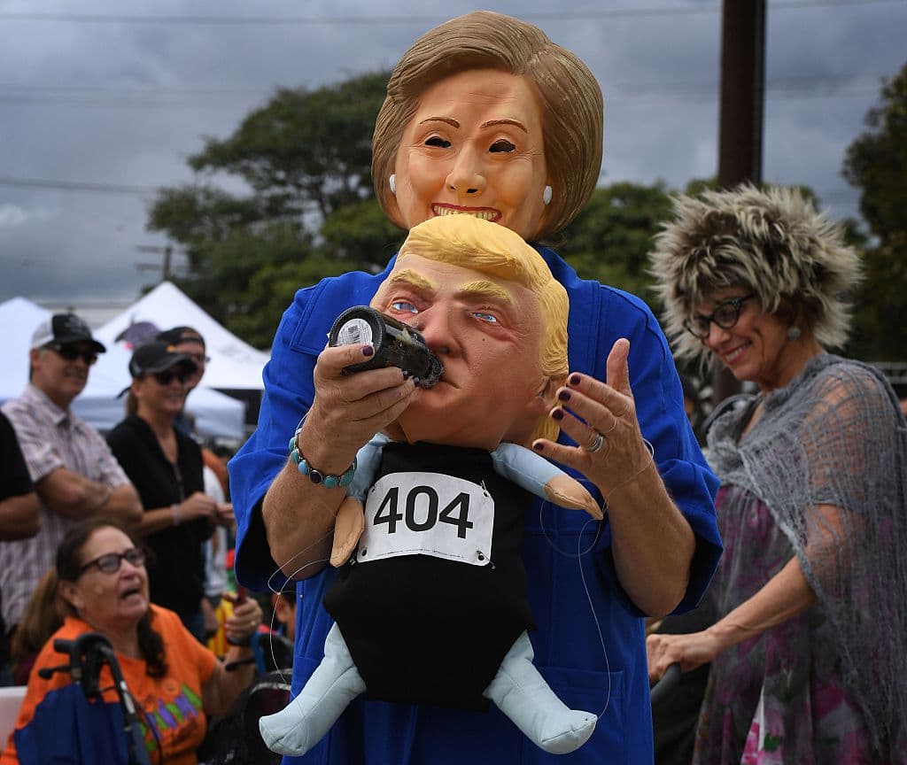 Una mujer con una máscara de Clinton carga un muñeco que se asemeja a un Trump bebé en una parada de Halloween en Long Beach, California. (Mark Ralston/AFP/Getty Images)