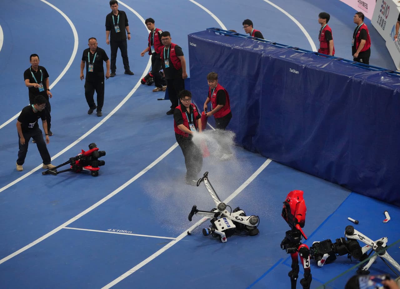 Los oficiales extinguen el fuego de un robot humanoide después de que chocara contra la barrera al final de la carrera de 100 metros.