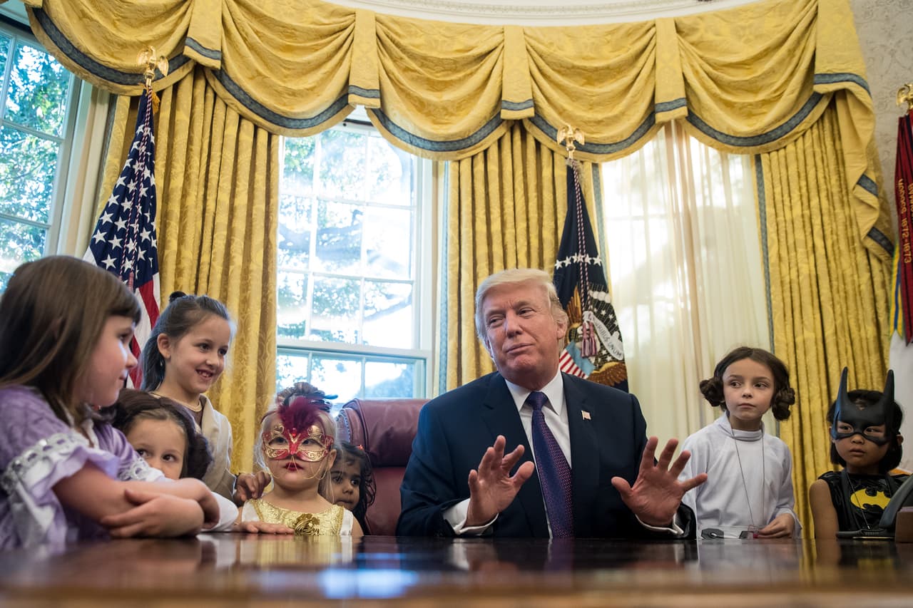 <b>Acorralado por los (hijos de los) periodistas.</b> El día de Halloween de 2017 el presidente Donald Trump recibió en el Salón Oval a los hijos de los corresponsales que cubren las noticias en la Casa Blanca. En un momento del peculiar encuentro el presidente hizo un gesto en el que parece defenderse de la avalancha de preguntas de los pequeños, enmascarados para la ocasión.
