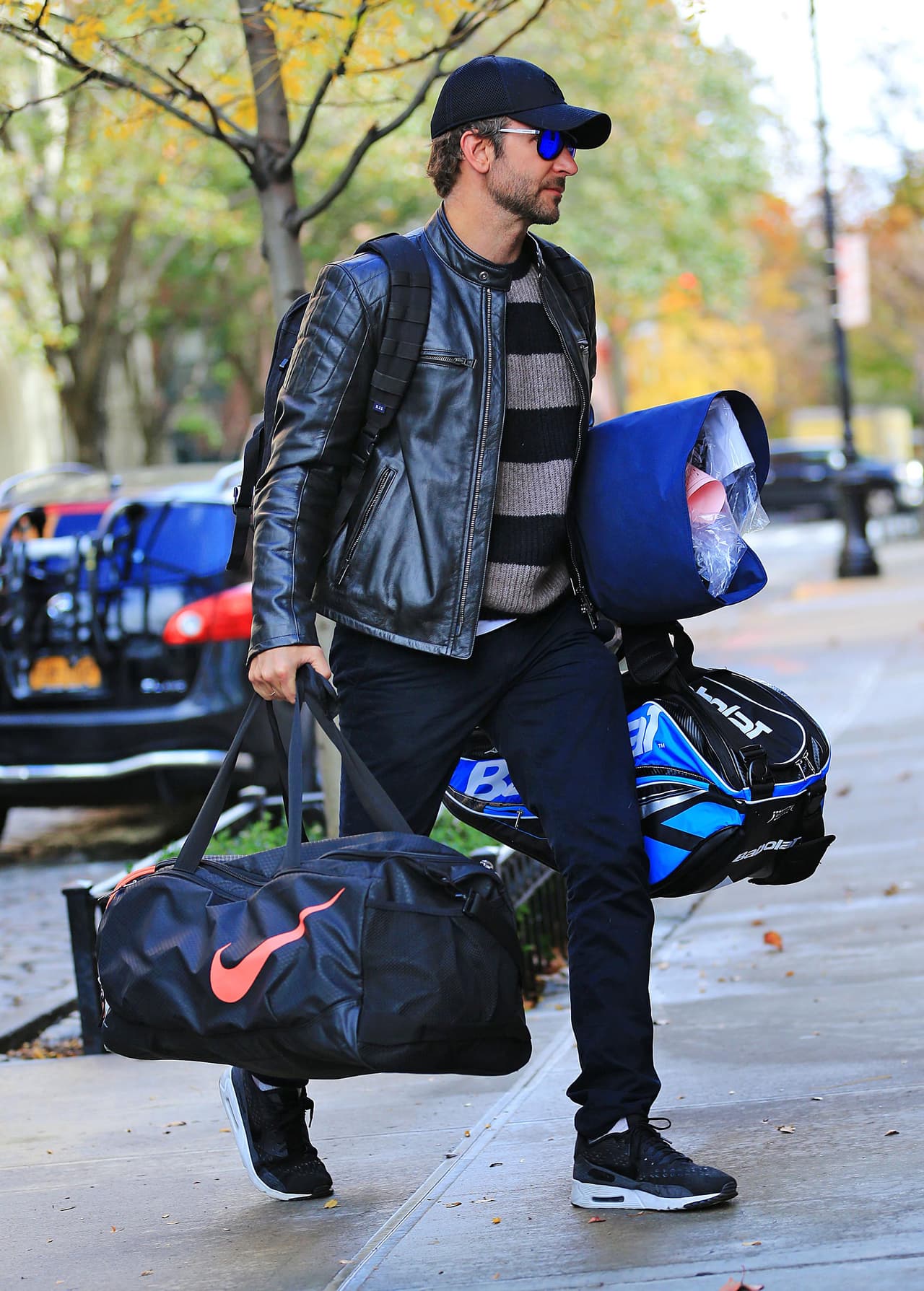 Bradley Cooper cargando muchas maletas y mochilas.