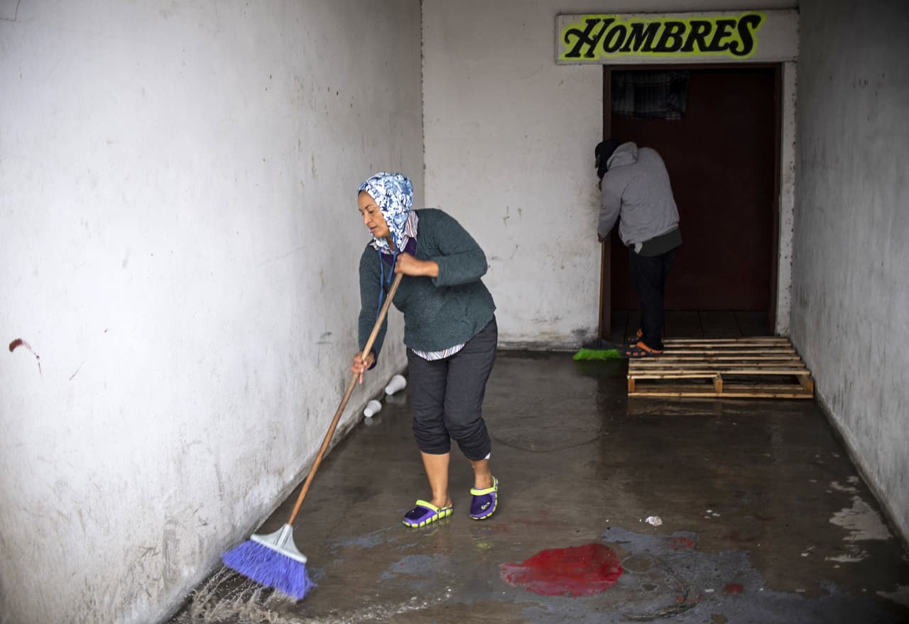 Central American migrants -mostly from Honduras- traveling in a caravan to the United States, wash the floor after being relocated at a new temporary shelter in east Tijuana, Baja California State, Mexico, in the border with the US on November 30, 2018. (Photo by PEDRO PARDO / AFP) (Photo credit should read PEDRO PARDO/AFP/Getty Images)