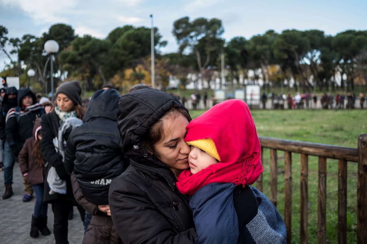 Nancy and her 3-year-old son, from El Salvador, stand in line outside an immigration office in Madrid to request apply in Spain. She and her husband Oscar say they fled their country because of gang violence.