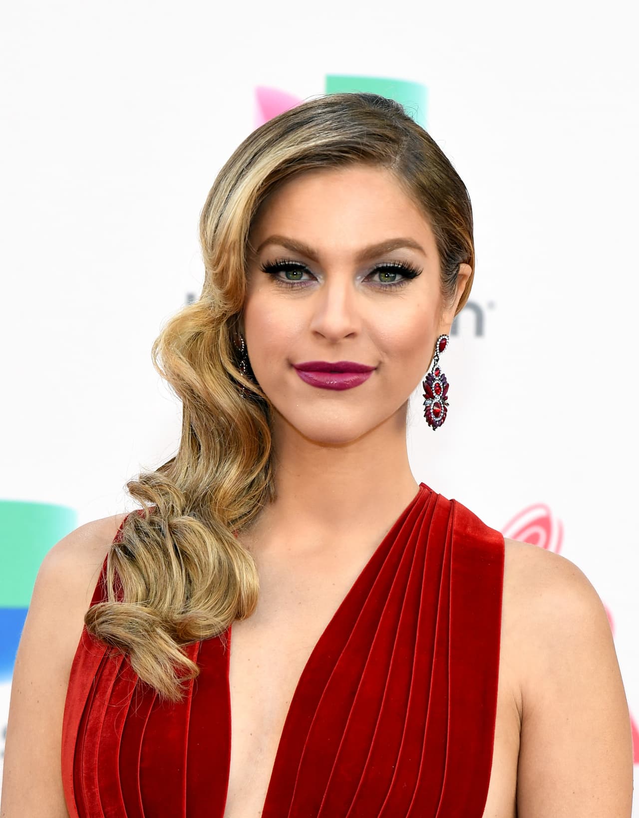 Daniela di Giacomo con peinado tipo años 50, ondas al agua y pelo de lado destacando un largo pendiente. Desafió la tendencia llevando labios violetas.