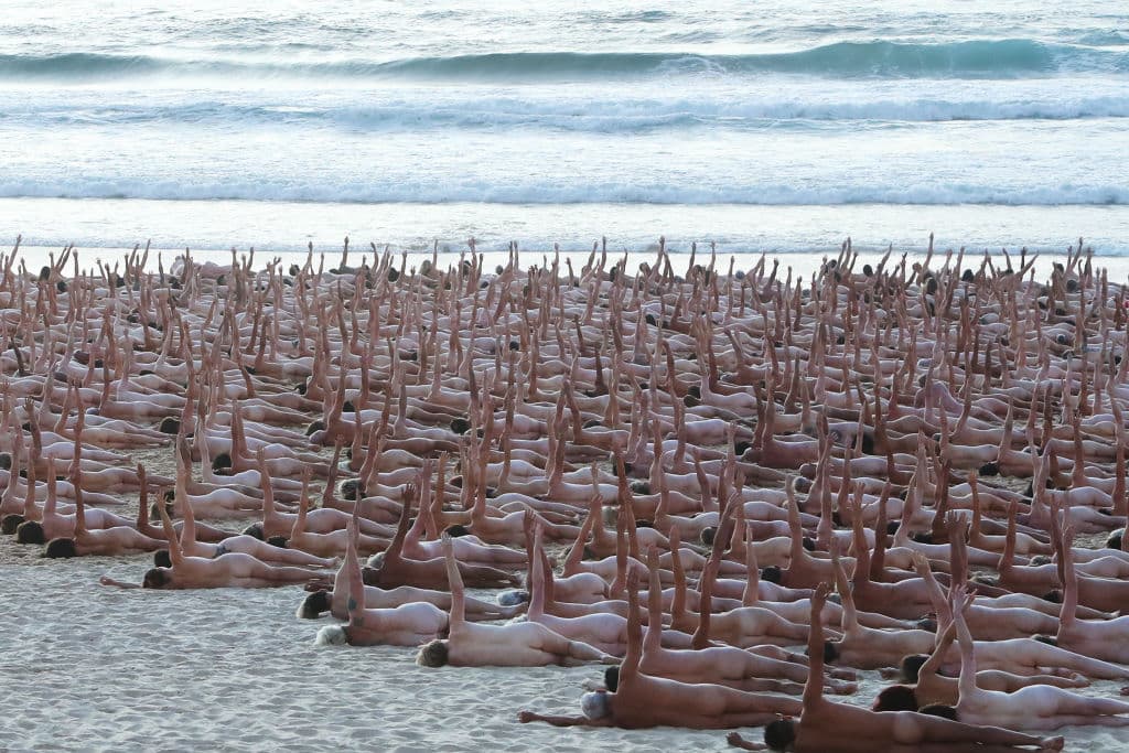 Desndos sobre la arena, tumbados de lado y con el brazo levantado hacia el cielo, una de las posiciones en las que posaron los voluntarios.