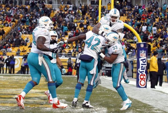 Los fanáticos de los Dolphins ya no hablan de la controversia Incognito/Martin, ni si Ireland o Philbin estarán con el equipo en el 2014, sino que pasan horas calculando… ¡porque tenemos chance de ir a los playoffs! Al principio de la temporada, y sobre todo, después de perder -casi deshonrosamente- contra Tampa Bay y Buffalo, los comentarios sobre Miami eran negativos. Qué si las novatadas, qué si Tannenhill, qué si el running game, qué si la línea ofensiva, que si… qué se yo… Pero ahora, las cosas han cambiado y solo se mencionan las posibilidades que tenemos de jugar en enero. ¡Ay, bendito! Bueno, después de este encontronazo con los portadores de las terribles toallas amarillas, donde salimos vencedores … por media pulgada… 34-28, ya todo me parece posible. Arriba Tannenhill (20 de 33, para 200 yds); arriba Wake and Odrich; arriba Thomas (105 yds, un TD en 16 acarreos); arriba Clay con sus dos TD y arriba Philbin, que mantiene el invicto en la revisión de las jugadas (obtuvo el cambio de “incomplete pass” a TD de Hartline). ¡Arriba, Dolphins, seguimos cuesta arriba!