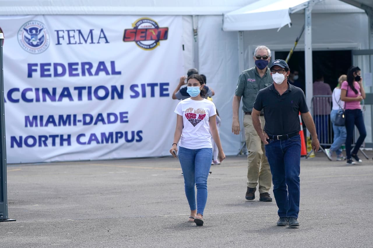 Azul Thurdekoos, de 16 años, a la izquierda, camina con su padre Ricardo después de recibir la vacuna de Pfizer en un centro de vacunación de FEMA en el Miami Dade College, en Miami. 
<a href="https://www.univision.com/local/miami-wltv/menores-de-16-y-17-anos-podran-ponerse-la-vacuna-de-pfizer-conren-florida">Cualquier adulto en Florida es ahora elegible para recibir la vacuna</a> contra el coronavirus. Además, el estado anunció que los adolescentes de 16 y 17 años también pueden ser vacunados con el permiso de sus padres.