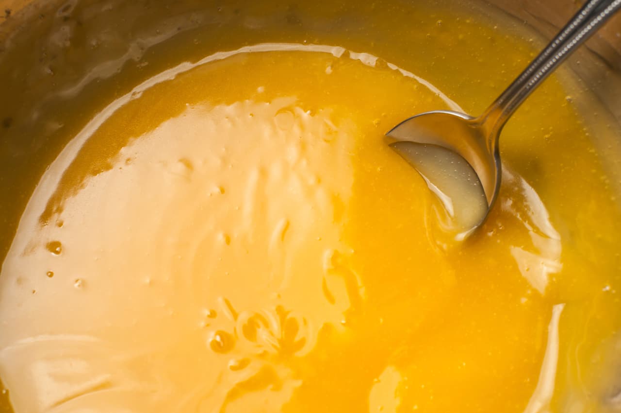 Pon una olla a fuego medio donde vas a ir incorporando el jugo de naranja, el vino blanco, la salsa de soja, los ajos enteros. Revuelve bien y añade el azúcar rubia y la maicena, después la kétchup.