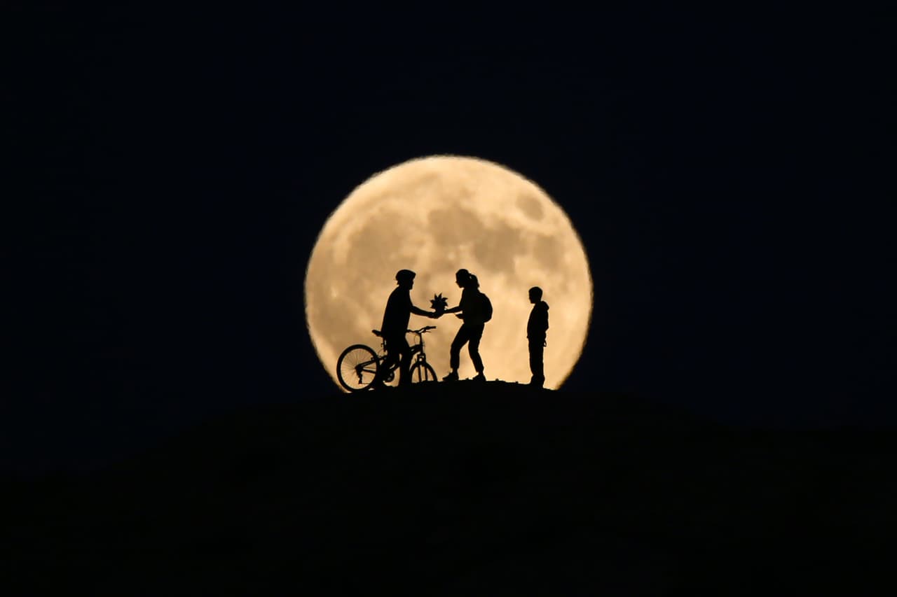 Otra imagen con las siluetas de personas frente a la Luna llena que se levanta antes de la fase total del eclipse más largo del siglo en Van, Turquía.