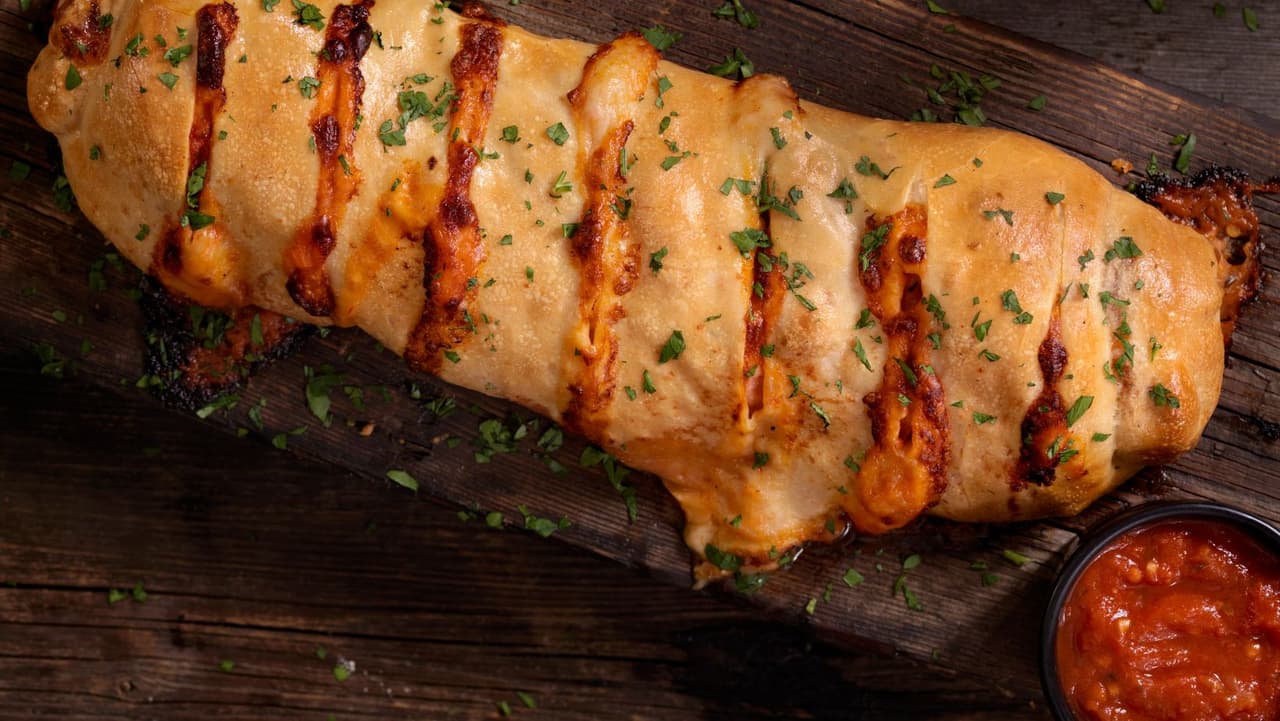 <b>Stromboli</b>: Esta corteza de masa dorada y crujiente rellena de queso derretido, verduras, carnes saladas y, a veces, mostaza, en realidad se originó en Filadelfia. En la década de 1950, los italoamericanos inventaron el plato y le dieron el nombre del volcán Stromboli, que se encuentra en la isla de Stromboli en Italia.