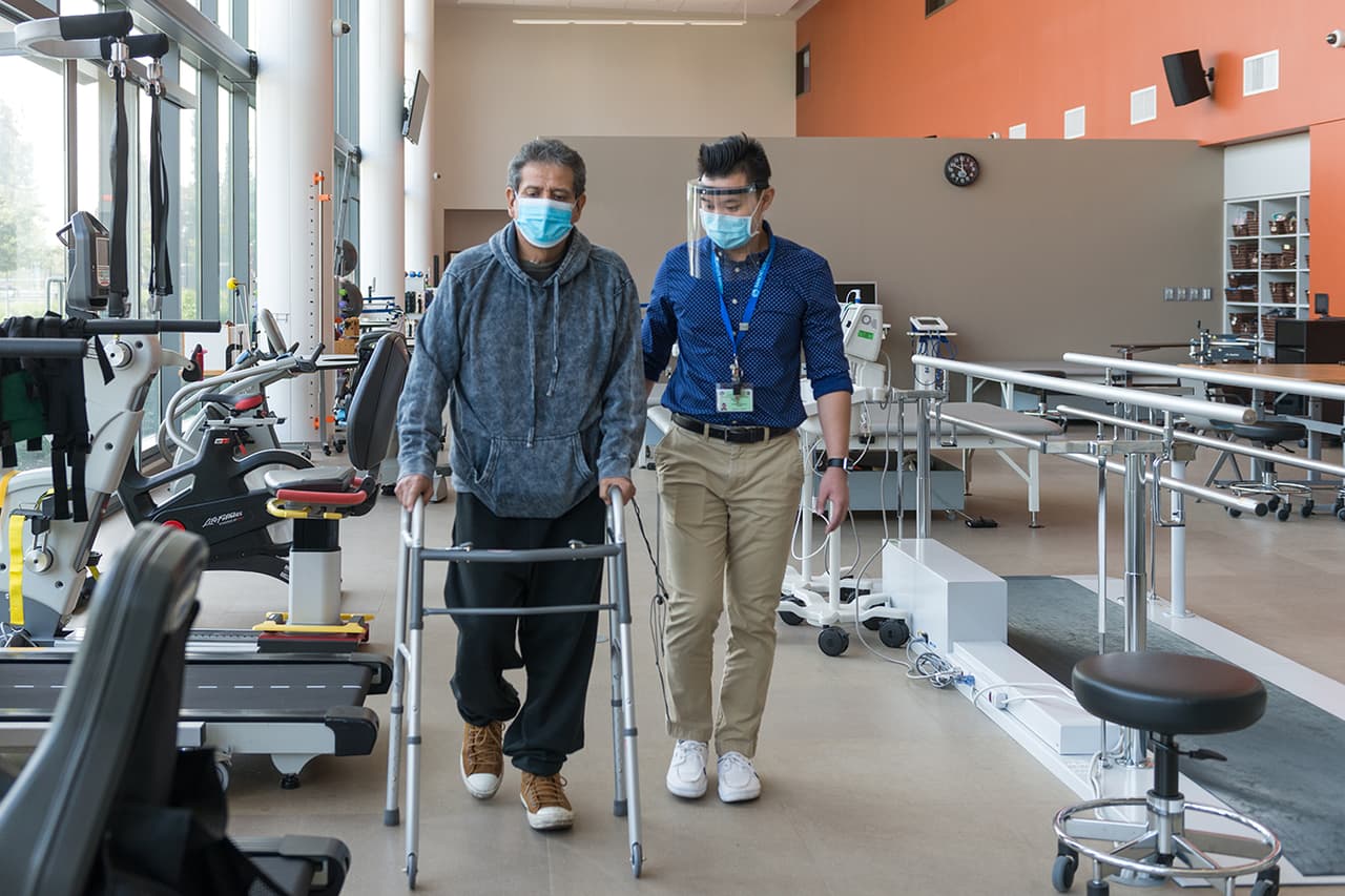 Pérez Castro camina mientras su terapeuta físico toma el tiempo.