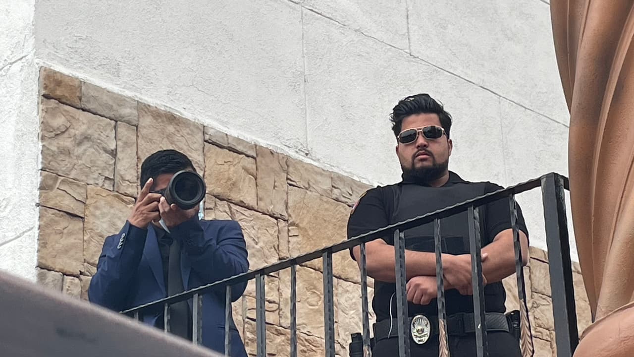 Un miembro de la iglesia fotografiaba a los manifestantes, a un lado de un guardia armado.