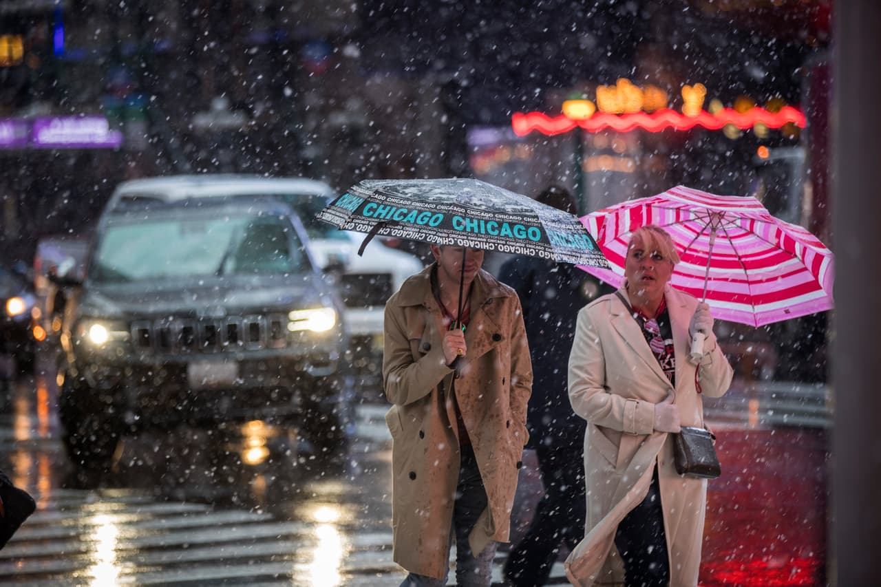Peatones se cubren de la nieve mientras cruzan una intersección en Times Square, Nueva York.