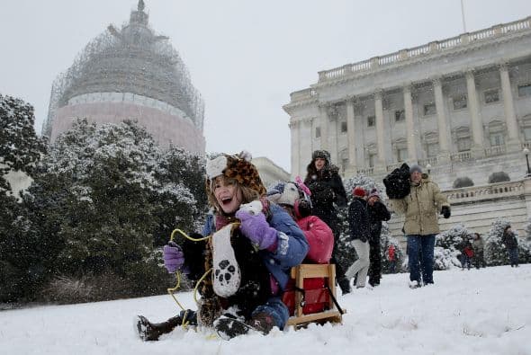 Claire McKeon y Megan Krepp se lanzan en un trineo por una ladera cubierta de nieve frente al Capitolio.