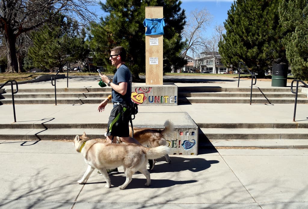 Un hombre pasea a sus perros junto a un busto cubierto de César Chávez en el Parque César E. Chávez de Denver, el jueves 19 de marzo de 2026.
