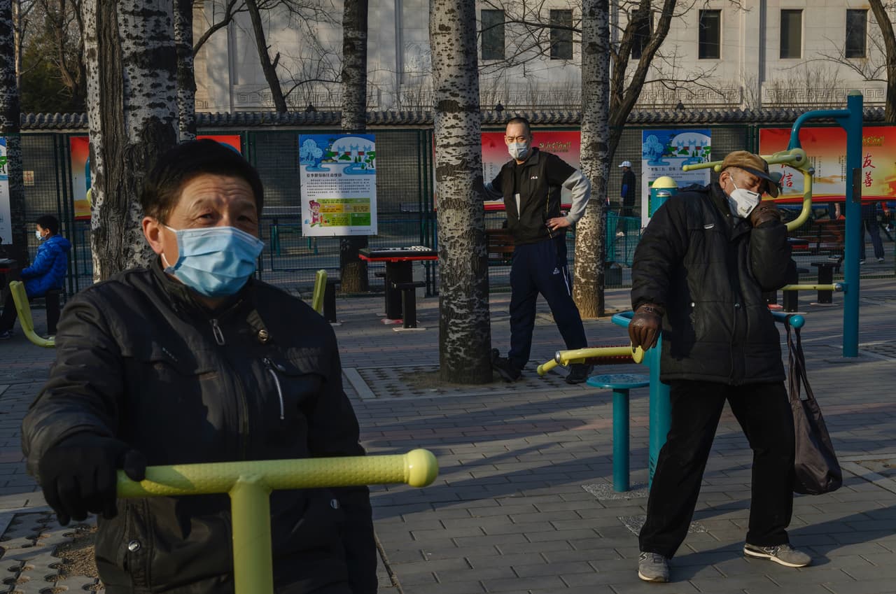 Un grupo de hombres hace ejercicios portando sus mascarillas en una plaza de Pekín.