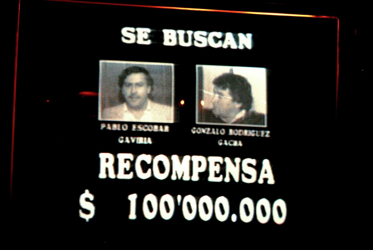 La imágen, tomada de una transmisión de televisión de unas semanas antes de la explosión del avión, muestra 
<b>la recompensa ofrecida por el gobierno a quien diera información por Escobar </b>y uno de sus compañeros del Cartel de Medellín, Gonzalo Rodríguez Gacha. Se ofrecían 100 millones de pesos, unos
<b> 250,000 dólares.</b>