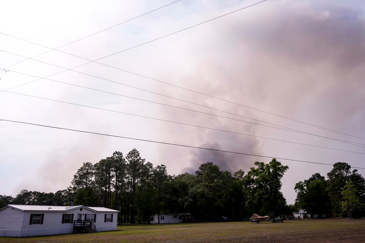 El incendio del camino Pineland, en el condado Brantley, arde detrás de varias viviendas, el miércoles 22 de abril de 2026, cerca de Nahunta, Georgia. (AP Foto/Mike Stewart)