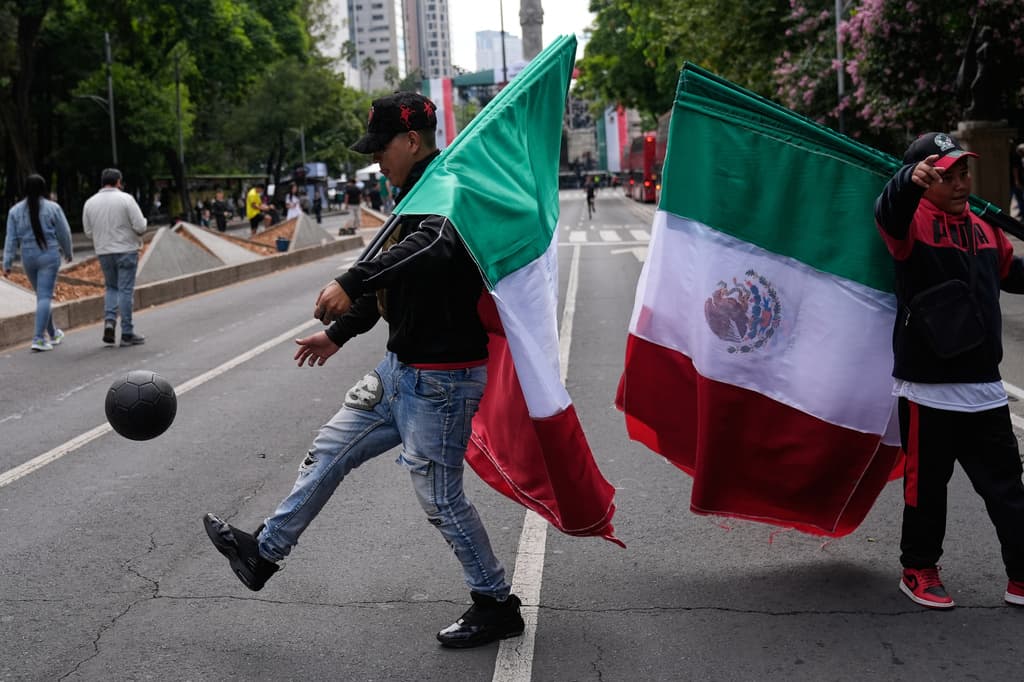Vendedores de banderas mexicanas patean un balón de fútbol a lo largo del Paseo de la Reforma