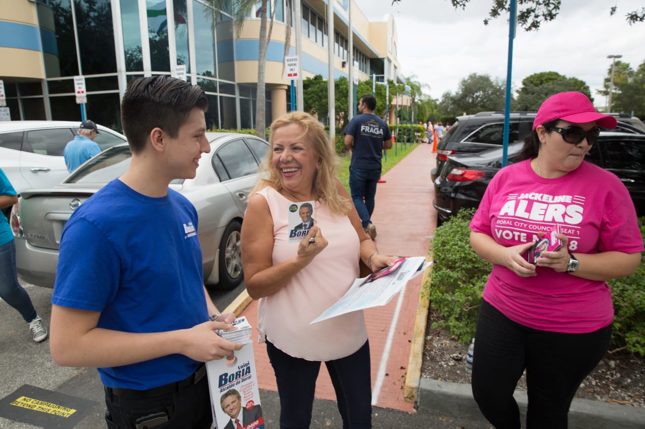 Varios representantes de los candidatos a alcalde de la ciudad de Doral esperan en su límite para abordar a los votantes. David Felipe Nivia, representante de la campaña por la reelección del alcalde Luigi Boria aseguró que “mucha gente sale a votar temprano, imagínate, ya hay líneas, si solo fuera un día no alcanzarían las horas. Así la gente puede planificar, muchas personas trabajan a tiempo completo en esta comunidad”.
