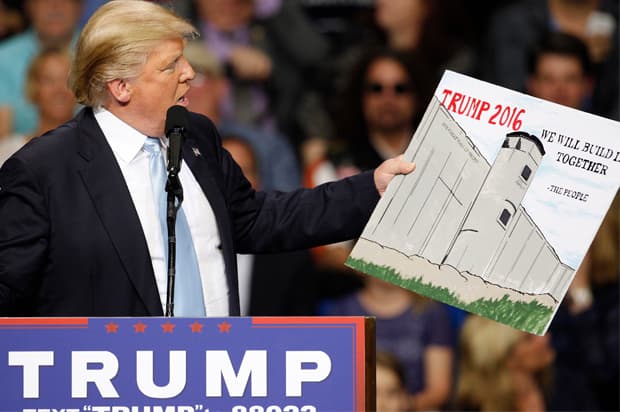 U.S. Republican presidential candidate Donald Trump holds a sign supporting his plan to build a wall between the United States and Mexico that he borrowed from a member of the audience at his campaign rally in Fayetteville, North Carolina March 9, 2016. Trump was interrupted repeatedly by demonstrators during his rally.