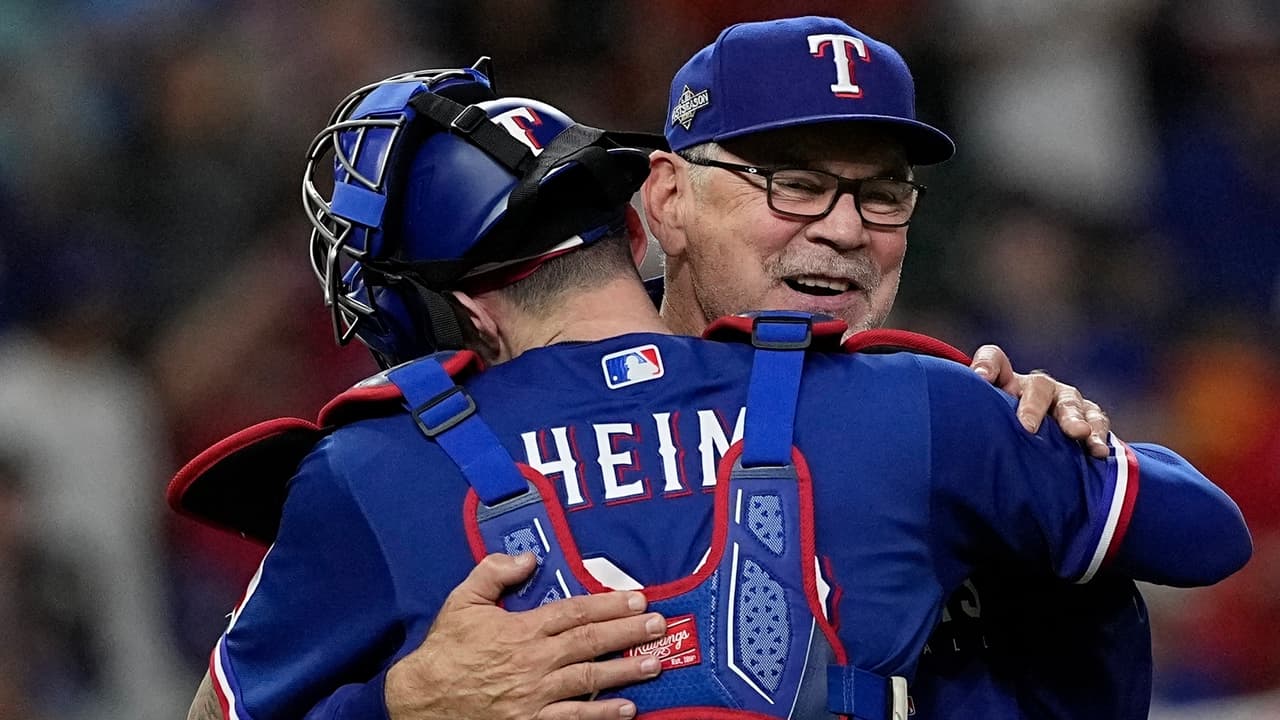 Bruce Bochy, mánager de los Rangers de Texas, abraza a Jonah Heim.