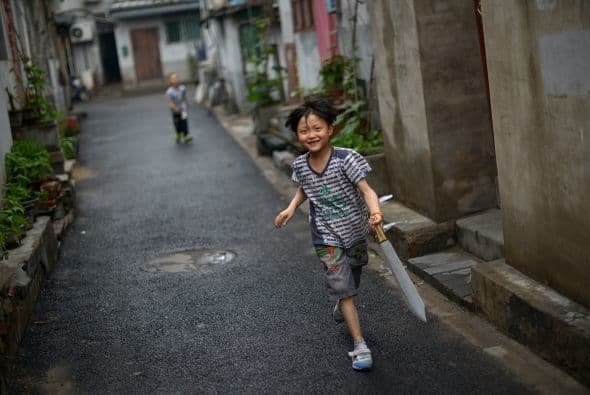 Un niño corre a través de un callejón en Beijing.