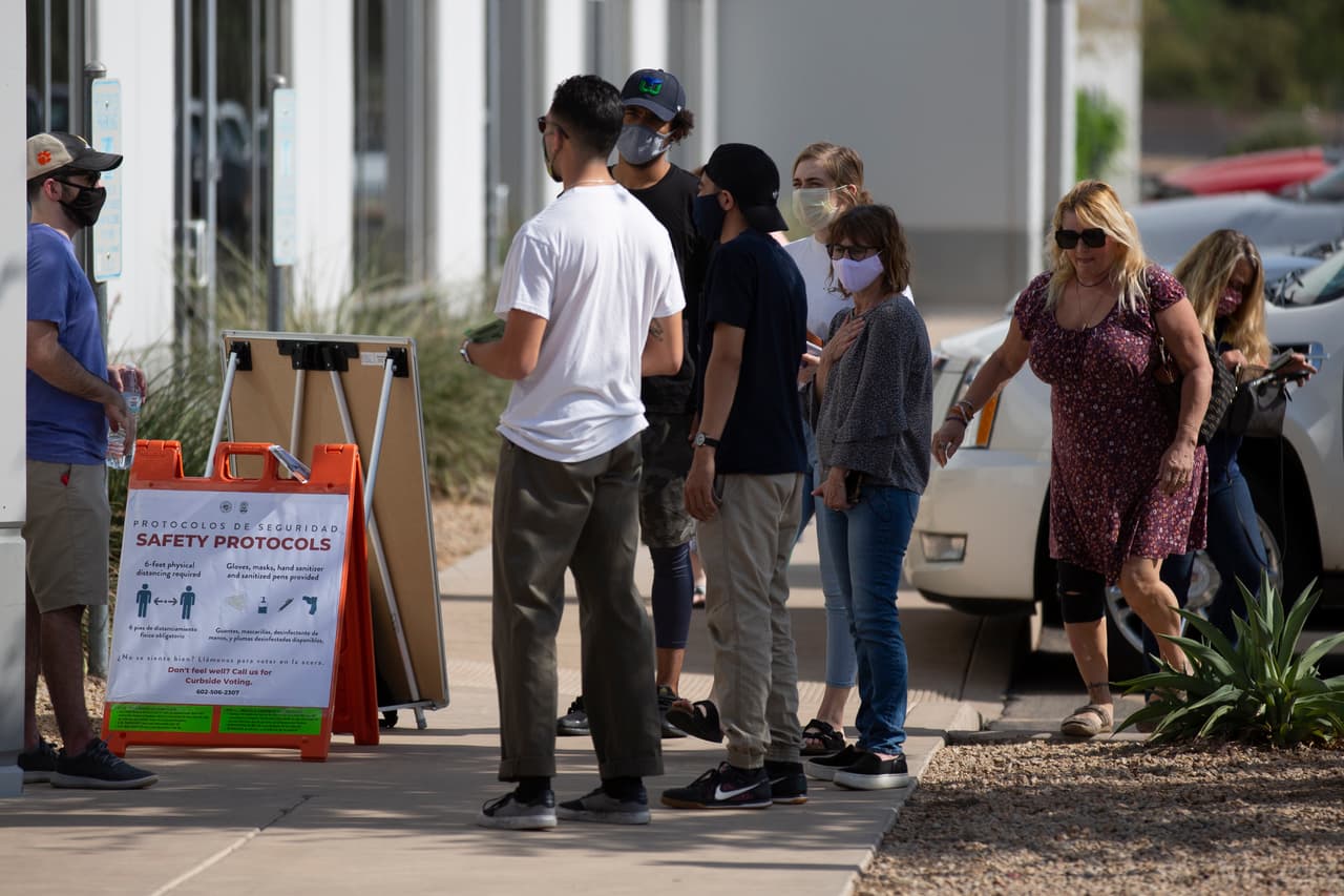 Los votantes que llegan reciben instrucciones de seguridad de un trabajador electoral en la mesa de votación de Living Word Bible Church en Phoenix, Arizona, el martes 3 de noviembre de 2020 el día de las elecciones.