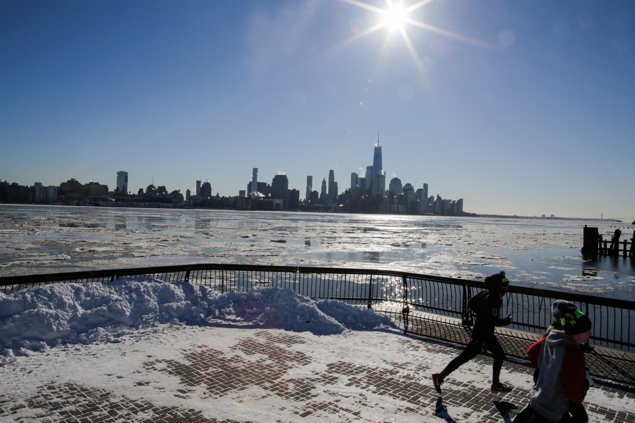 La gente trota mientras el hielo flota a lo largo del río Hudson con el fonde de los rascacielos de la ciudad de Nueva York, vistos desde Hoboken, Nueva Jersey.