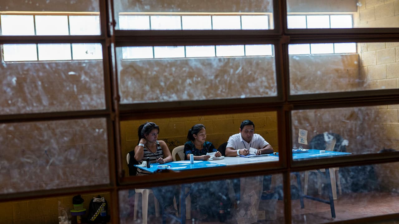 Los trabajadores electorales esperan a que las personas emitan sus votos, en Chinautla.