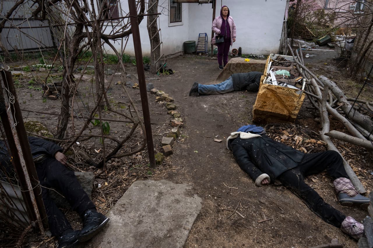 El sombrío trabajo para Minchenko y un pequeño grupo de otros comenzó bajo la ocupación cuando los cuerpos esparcidos por las calles o arrojados apresuradamente en los patios. En la imagen, una mujer junto a tres cadáveres en el patio
<a href="https://www.univision.com/noticias/mundo/horrores-bucha-retirada-ejercito-ruso" target="_blank">de una casa en Bucha</a>, a las afueras de Kiev.