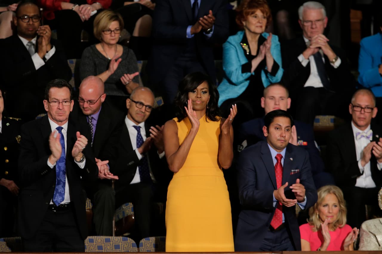La primera dama, Michelle Obama, y sus invitados aplauden durante el discurso del presidente.