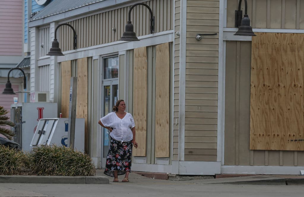 Una mujer mira a la playa frente a un edificio tapiado, antes de refugiarse por la llegada del huracán Laura, en Galveston, Texas.