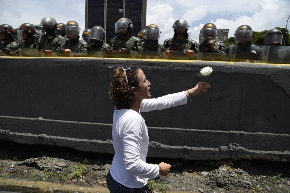 A woman dressed in white offers a flower to riot troops during a woman's march, May 6, 2017