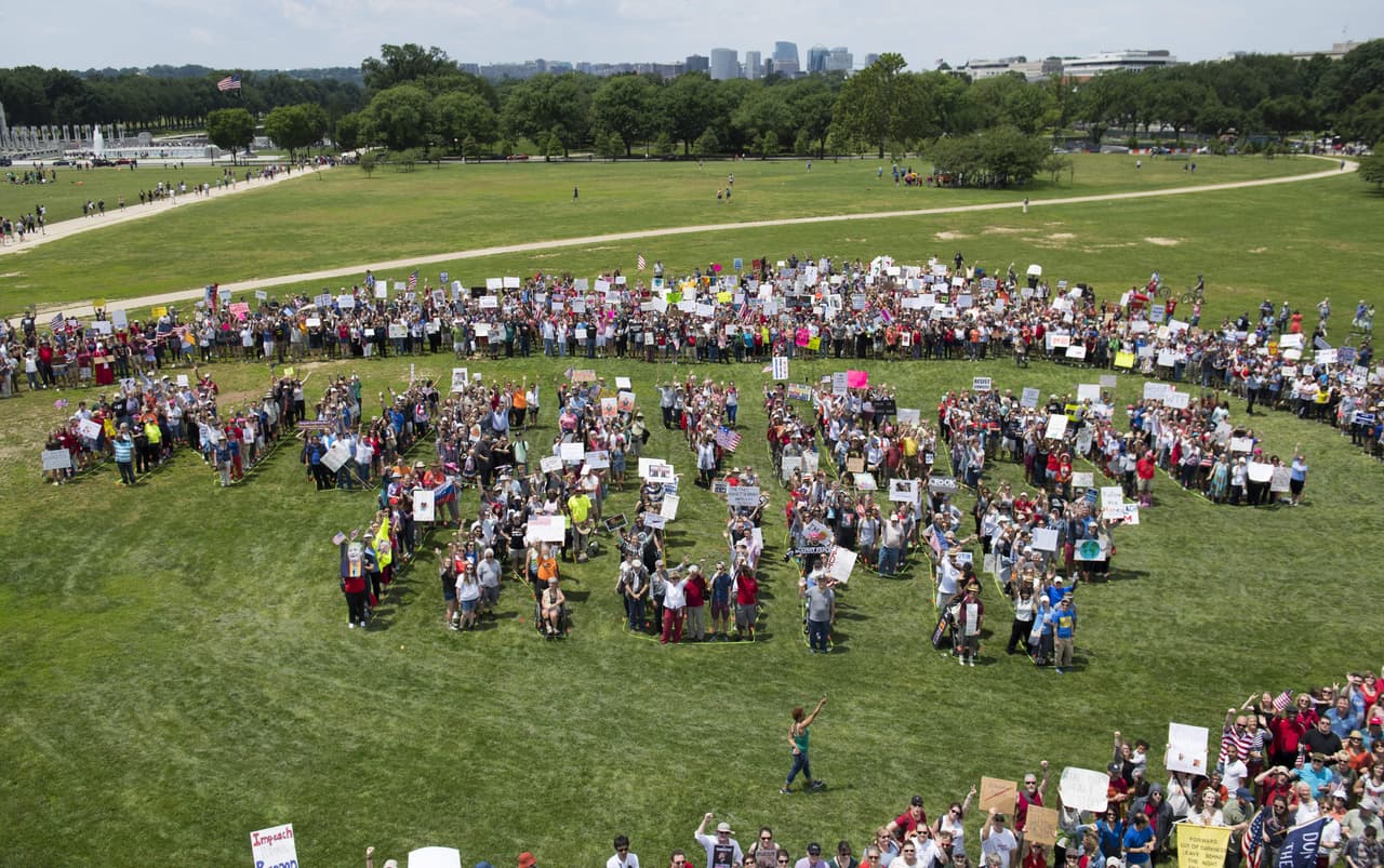 Un grupo de manifestantes forman las palabras 
<b>'Investigate Trump' (Investiguen a Trump) en el Mall de Washington DC. </b>
