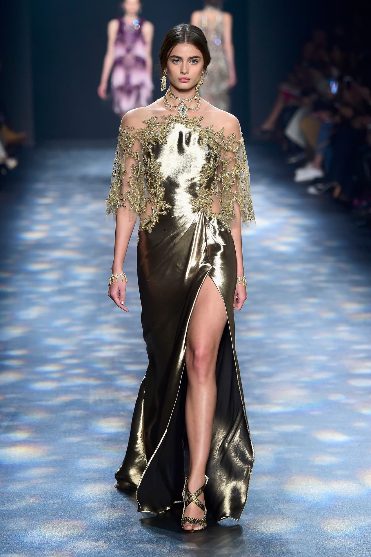 Si alguien sabe de vestidos de gala, es la firma Marchesa, demostrándolo en este líquido vestido dorado con un corte sesgado que cae sobre el cuerpo como una cascada. Las mangas apenas sugeridas por el delicado encaje , y el cuello delineado por un collar, son el tipo de detalles que pueden hacer que Roselyn rebase todas las expectativas. 
<br>