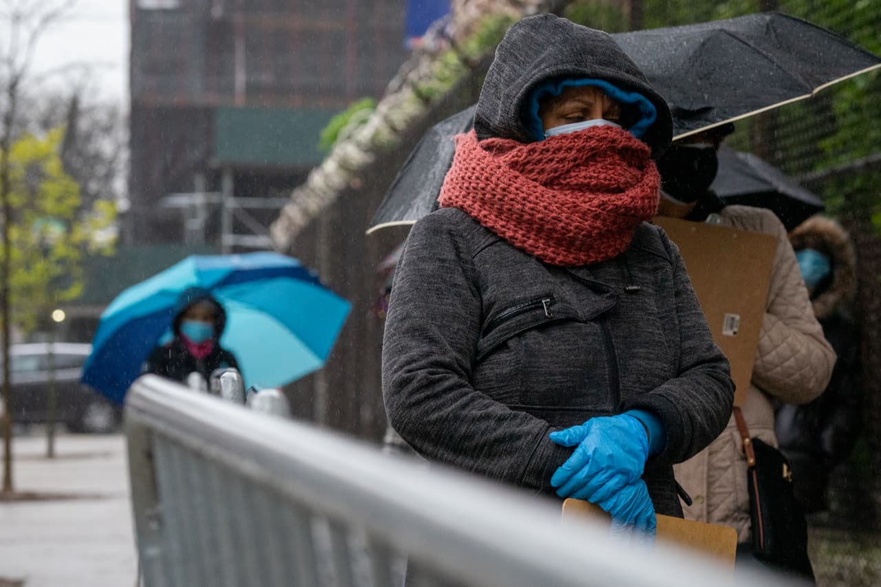 Una mujer usa una bufanda, encima de su mascarilla quirúrgica, para protegerse